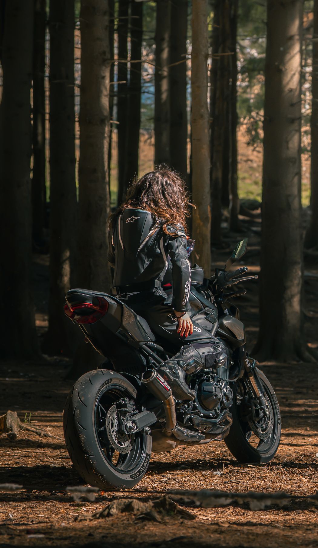 Caterina seduta in moto in una pineta